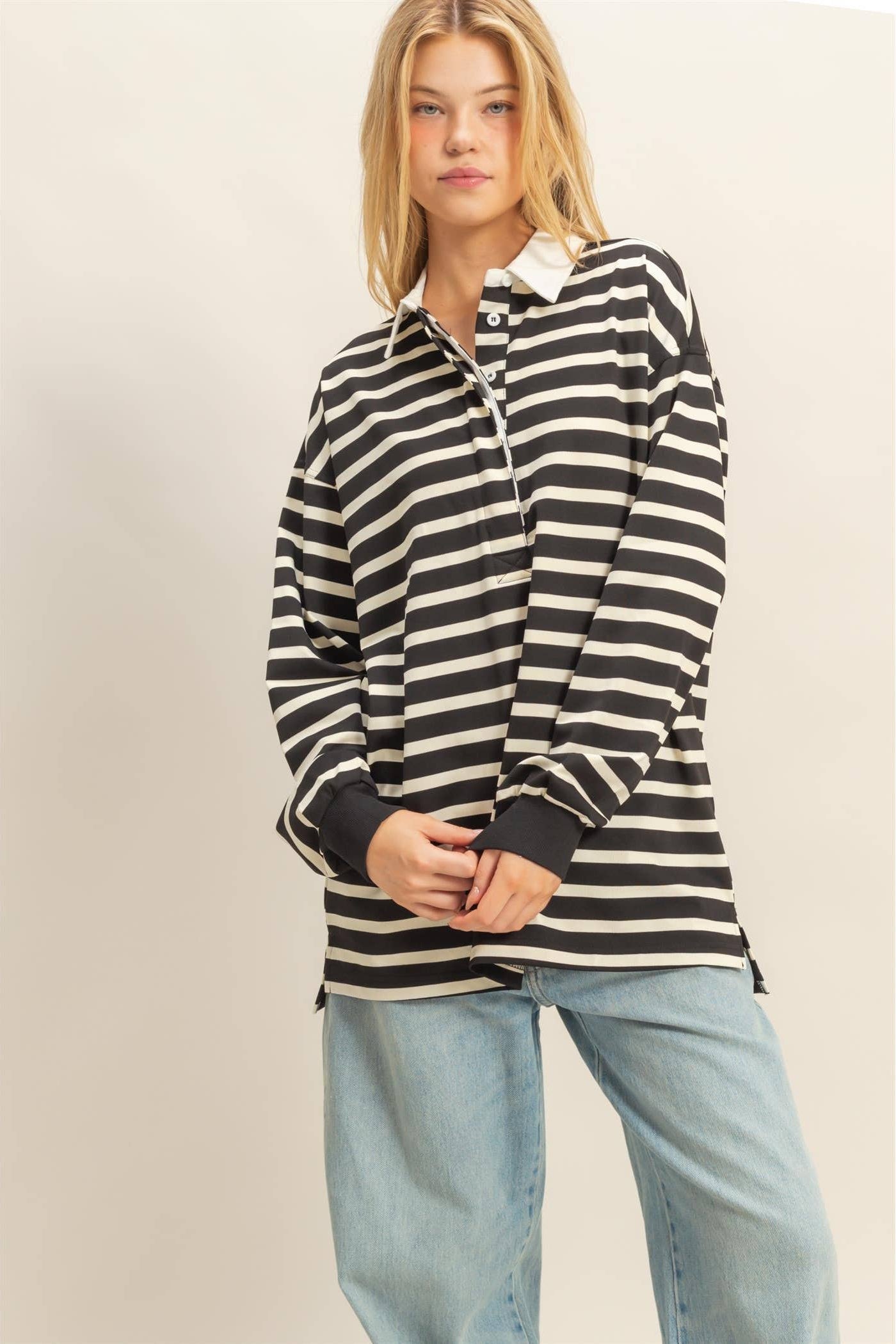 Person wearing a black and white striped shirt with light blue jeans on a beige background