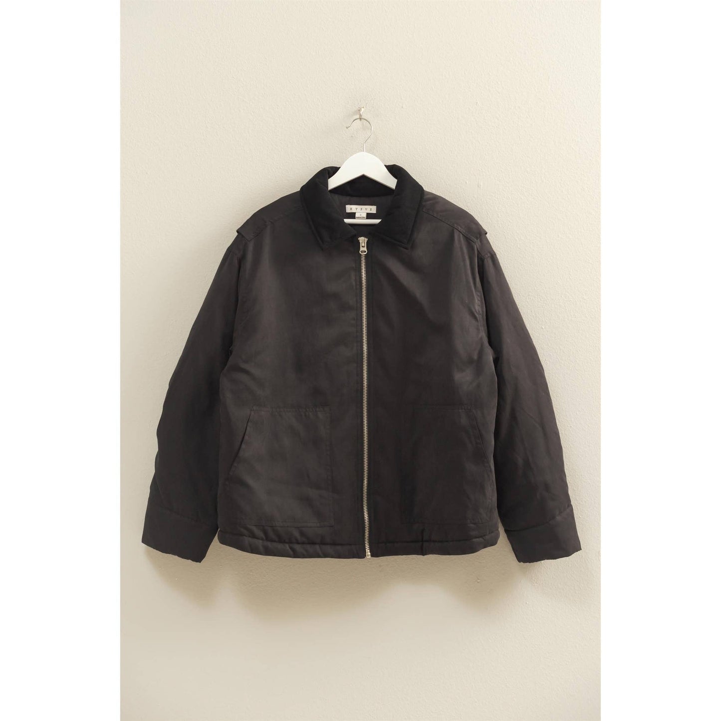Black jacket on a hanger against a beige wall