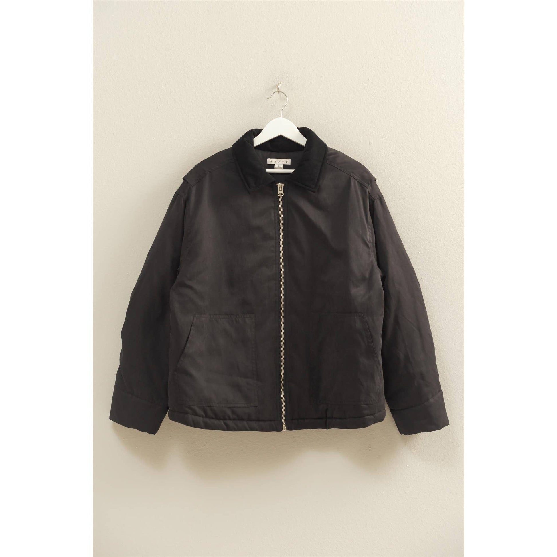 Black jacket on a hanger against a beige wall