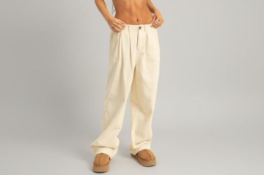 Person wearing cream-colored pants with a plain background